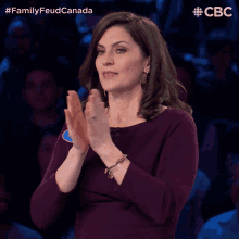a woman in a purple dress is applauding in front of a crowd and the words family feud canada are above her