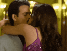 a woman in a purple dress is kissing a man in a suit
