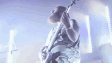 a man with a beard is playing a guitar on a stage in front of a microphone .