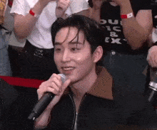 a man is holding a microphone in front of a crowd .