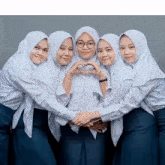 a group of girls are posing for a picture and one of them is making a heart with her hands