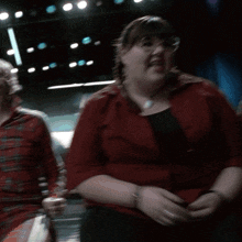 a woman wearing glasses and a red shirt is sitting in a dark room