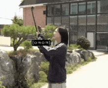 a woman is taking a picture of a tree with a sign that says ' iooo ' on it