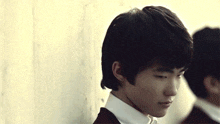 a young man leaning against a wall looks down