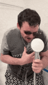 a man wearing a star wars shirt is holding a shower head in front of his face