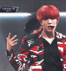 a young man with red hair is wearing a red and black jacket