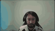a man with a beard and headphones is sitting in a chair .