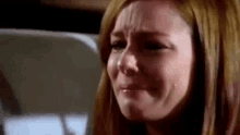 a woman is crying with tears running down her face while sitting in a chair .