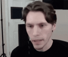 a man in a black shirt is making a funny face while talking on a video call .