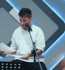 a man singing into a microphone while holding a piece of paper in front of him