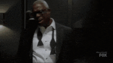 a man in a suit and tie is covering his mouth with his hand