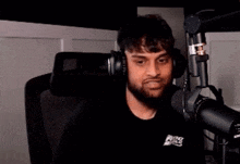 a man with a beard is sitting in front of a microphone in a room .