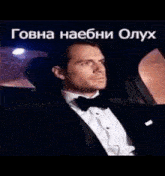 a man in a tuxedo is sitting in the back seat of a car .