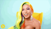 a woman with rainbow hair and earrings is smiling in a yellow chair