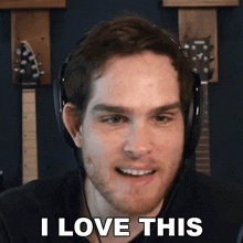 a man wearing headphones says " i love this " in front of some guitars