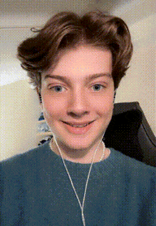 a young man wearing headphones and a blue shirt is smiling for the camera .
