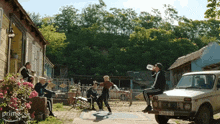 a group of people are drinking from a bottle while sitting on the back of a car that says prime on it