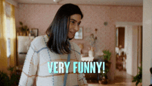 a woman in a plaid sweater says " very funny " in a room