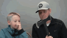 a man and a boy are holding an axe in front of their faces .