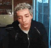 a young man with curly hair is sitting in front of a laptop computer .