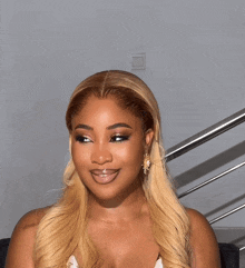 a woman with long blonde hair and earrings smiles for the camera