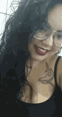 a woman with glasses and a tattoo of a dolphin on her chest smiles .