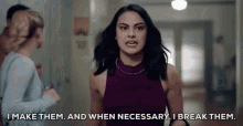 a woman in a purple dress is standing in a hallway talking to a man .