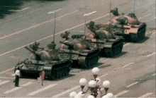 a row of military tanks are parked on a city street