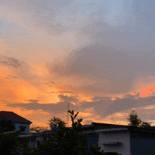 a sunset with a few buildings in the foreground and trees in the background