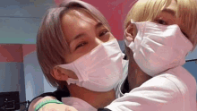 two men wearing face masks hugging each other .