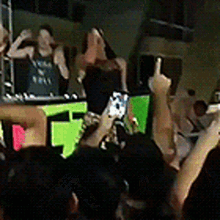 a group of people are standing in front of a dj playing music .