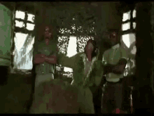 a group of people are standing in a room with a camouflage net behind them .