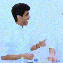 a man in a white shirt is talking to another man in a blue shirt