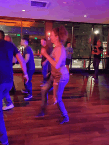 a group of people are dancing in a room with purple lights and a sign that says exit