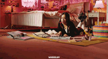 a girl is laying on the floor playing a keyboard with the word wheeluv on the bottom left
