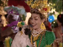 a woman in a green dress is holding a pug in her arms .
