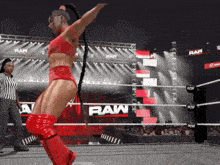 a woman is dancing in a wrestling ring while a referee watches .
