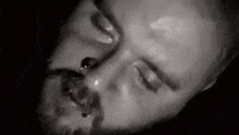 a close up of a man 's face with his eyes closed and a beard .