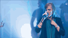 a woman singing into a microphone with a man standing behind her