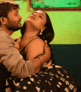 a man kisses a woman 's neck while she is wearing a black and white saree that says nepal