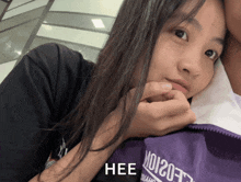a girl wearing a black shirt and a purple jacket that says hee