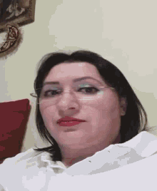 a woman wearing glasses and red lipstick is sitting in a room