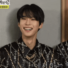 a man wearing a black shirt with gold chains around his neck is smiling