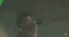 a young man is singing into a microphone on stage .