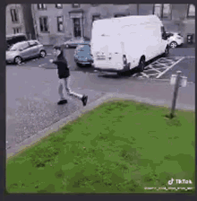 a man is running towards a white van that is parked on the side of the road .