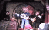 a man in a bear costume is playing a guitar in front of a sign that says pop