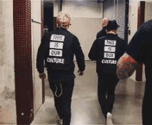 a group of people are walking down a hallway wearing black jackets that say this is our culture