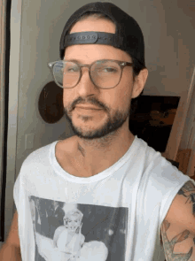 a man wearing glasses and a baseball cap has a tattoo on his neck