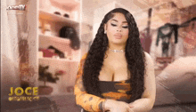 a woman with long curly hair is standing in front of a closet with clothes on shelves .