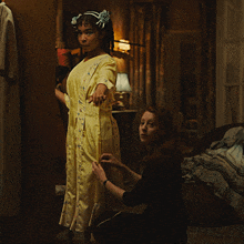a woman in a yellow dress is being helped by another woman in a black dress